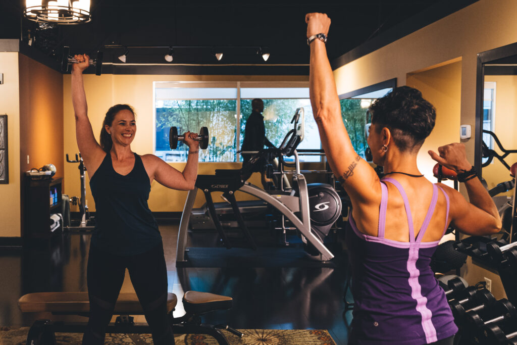 Woman with Personal Trainer Lifting Weights in Boutique Gy