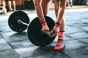 Person lifting weights in a gym, focused on strength training.